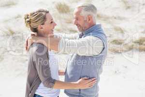 Happy hugging couple on the beach looking at each other
