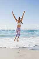 Sporty blonde jumping up on the beach