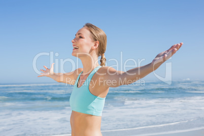 Fit woman standing on the beach with arms out