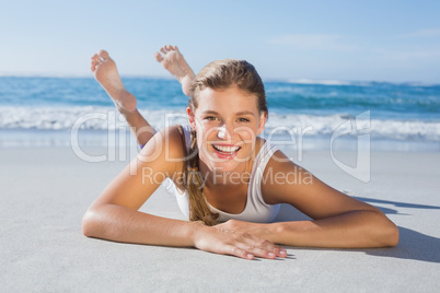 Sporty blonde lying on the beach smiling at camera