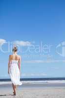 Blonde in white dress walking on the beach