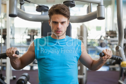 Focused man using weights machine for arms