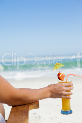 Woman sitting in deck chair with a cocktail at the beach