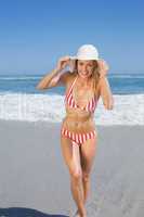 Gorgeous fit woman in striped bikini and sunhat at beach