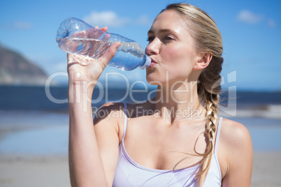 Focused fit blonde drinking water on the beach