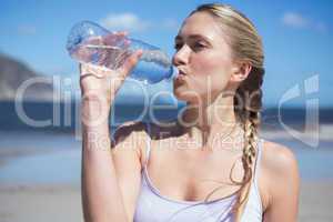 Focused fit blonde drinking water on the beach