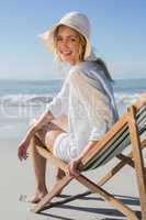 Smiling blonde relaxing in deck chair by the sea