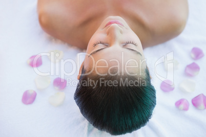 Calm brunette lying on towel with rose petals