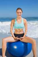 Fit woman sitting on exercise ball at the beach