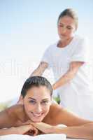 Happy brunette enjoying a massage poolside