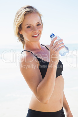 Fit blonde drinking water on the beach