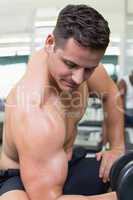 Handsome bodybuilder lifting heavy black dumbbell