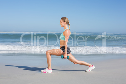 Fit woman doing weighted lunges on the beach