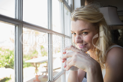 Pretty blonde sitting by the window having coffee