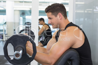 Focused bodybuilder lifting heavy black barbell