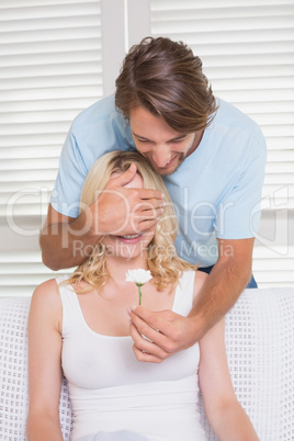 Man surprising his girlfriend with a flower on the couch