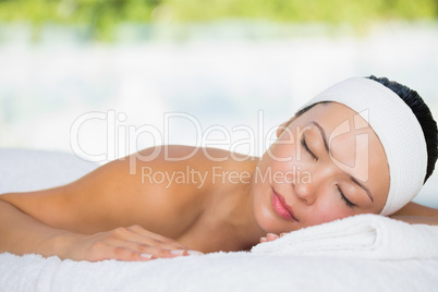 Smiling brunette lying on massage table with eyes closed