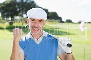 Happy golfer cheering at camera on putting green