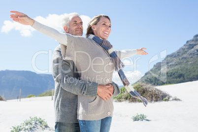 Carefree couple hugging on the beach in warm clothing