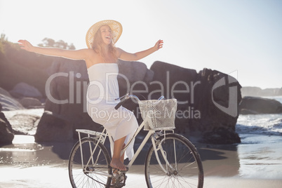 Beautiful blonde in white sundress on bike ride at the beach