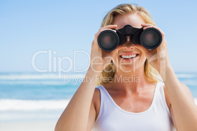 Blonde looking through binoculars on the beach