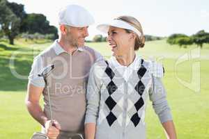 Golfing couple smiling at each other on the putting green