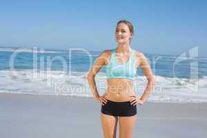 Fit woman standing on the beach with hands on hips