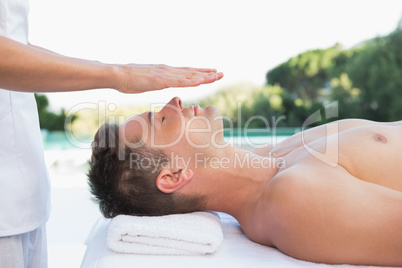 Peaceful man getting reiki treatment poolside Peaceful man getting reiki treatment poolside