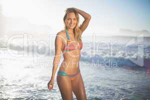 Happy blonde standing in the sea posing in bikini