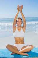 Fit calm woman sitting in lotus pose on the beach