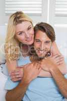 Happy casual couple sitting on couch smiling at camera