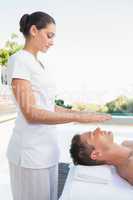 Peaceful man getting reiki treatment poolside