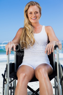 Wheelchair bound blonde sitting on the beach smiling at camera