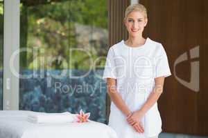 Smiling beauty therapist standing beside massage towel