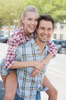 Young hip man giving his blonde girlfriend a piggy back