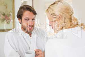 Cute couple in bathrobes having coffee together