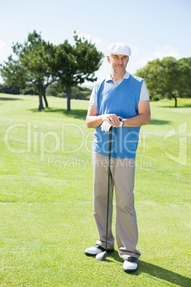 Cheerful golfer smiling at camera holding his club