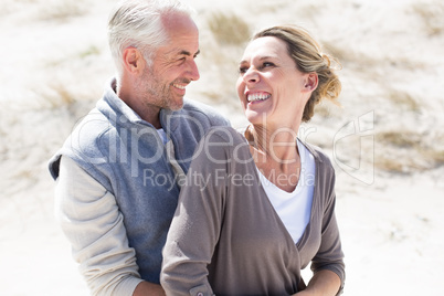 Happy hugging couple on the beach looking at each other