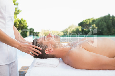 Peaceful man getting a head massage poolside