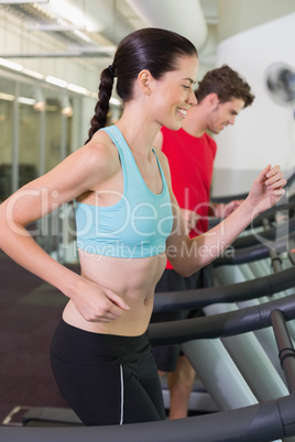 Fit happy couple running together on treadmills