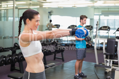 Fit brunette lifting blue dumbbell