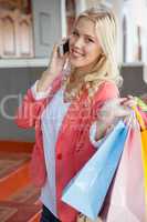 Pretty blonde smiling at camera holding shopping bags