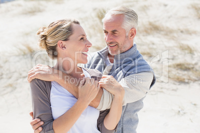 Happy hugging couple on the beach looking at each other