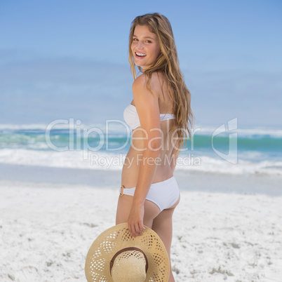 Beautiful happy blonde on the beach in white bikini holding sunh