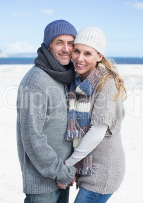 Smiling couple standing on the beach in warm clothing