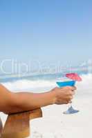 Woman sitting in deck chair with a cocktail at the beach