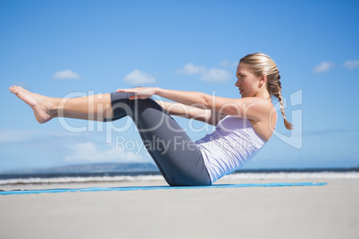 Focused fit blonde doing yoga on the beach