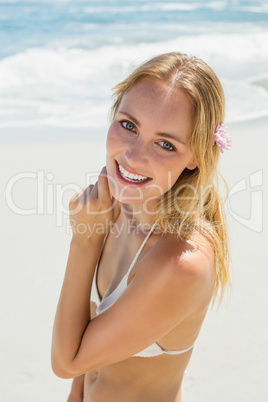 Beautiful blonde in white bikini smiling at camera on the beach