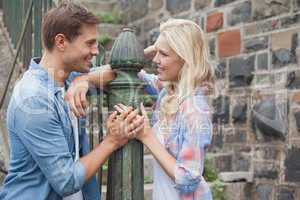 Hip young couple smiling at each other by railings