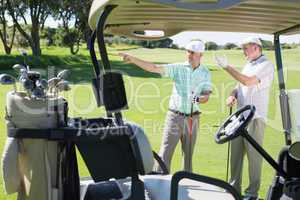 Golfing friends standing beside their buggy looking around